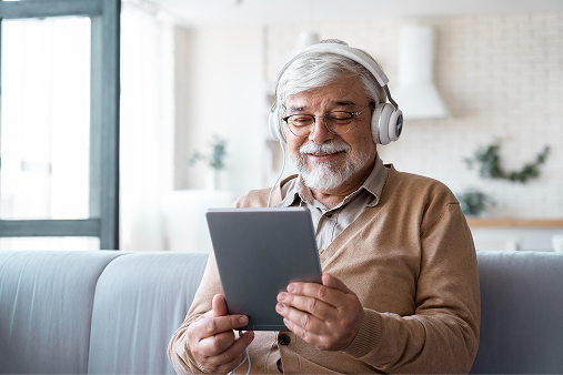 Pessoa idosa utilizando tablet com fones de ouvido